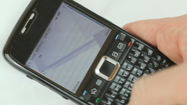 Typing and Texting - Male hand typing on smartphone qwerty keypad, message "I am still at work, please call back later" shows up on cell phone screen