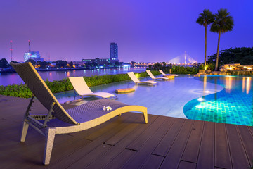 bed by tropical swimming pool near riverside at night in bangkok