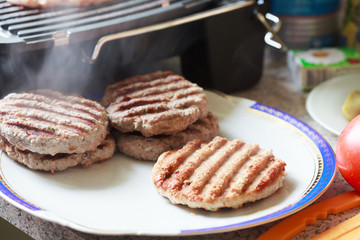 Cooking chicken and beef cutlets on the grill for burgers
