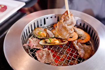 Mixed Roasted Meat and Seafood and Chopsticks on the BBQ Grill o