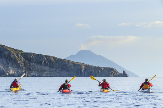 vier Seekajakfahrer paddeln auf Stromboli zu 