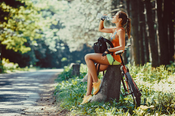 Pausing her mountain bike ride, female takes a break, admiring the natural beauty surrounding her in the forest. - obrazy, fototapety, plakaty