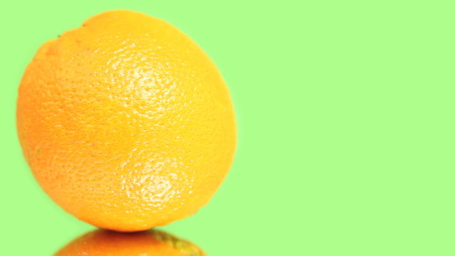 Fresh orange rotating on a green screen background, seamless loop.