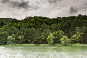 Natural lake with forest in the background and stormy clouds on the sky