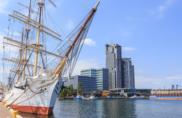 Fototapeta premium Gdynia nad morzem Bałtyckim. Statek Żaglowy (3 - masztowa fregata) zacumowany przy Molo Południowym Portu w Gdyni. W głębi widać wieże drapacza chmur