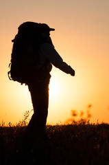 Hiker with backpack walking in the field