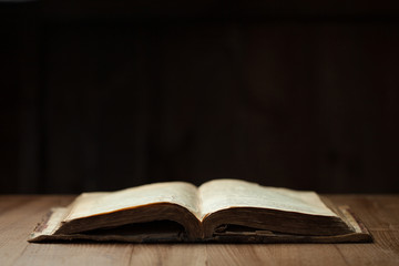 Image of an old Holy Bible on wooden background in a dark space