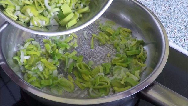 Stewing leek slices in a frying pan on a hot plate
