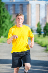Sporty man jogging in city street park. Outdoor fitness.