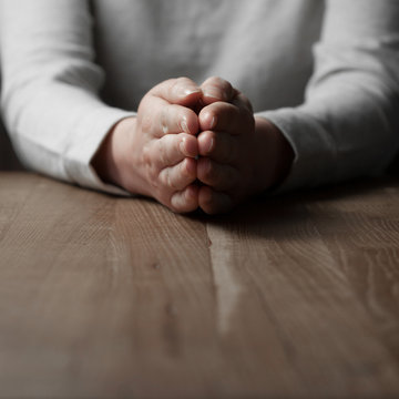 woman praying hands on wooden background