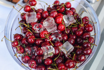 Cold fresh cherries in glass bowl on table/Fresh cherries and ice cubes in glass bowl on table