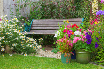 Cottage garden with bench and containers full of flowers