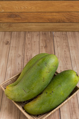 Mangoes in basket on wood background