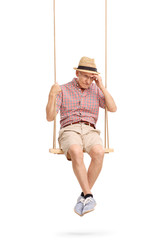 Depressed senior man sitting on a swing
