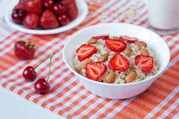 Helathy breakfast oatmeal porridge with strawberry, cherries and