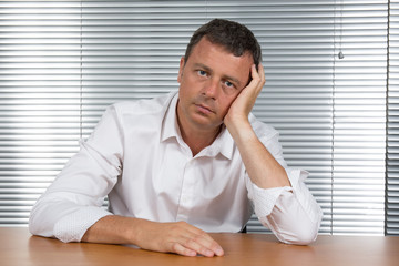 Worried businessman holding his head in his office