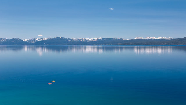 Photograph of two kayaks on calm Lake Tahoe with view on snowy peaks of Sierra Nevada mountains