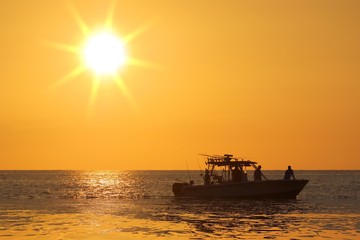 Silhouette of boat with golden sunrise.