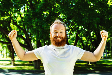 Happy man with red beard putting hands up as gesture of success