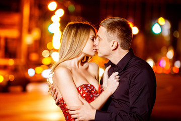 Handsome young man is kissing beautiful woman in red dress