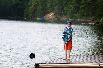 young boy at the lake wearing a swim band to protect his ears
