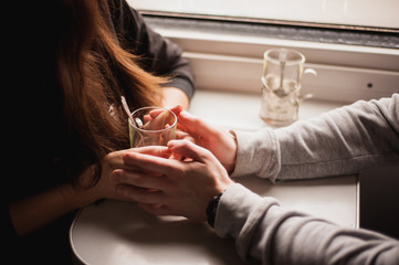 Four hands wrapped around a glass cup in train