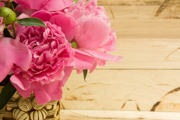 Floral frame with pink peonies on wooden background