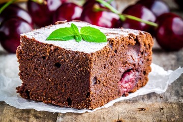 a piece of homemade chocolate brownie dessert with a cherry closeup