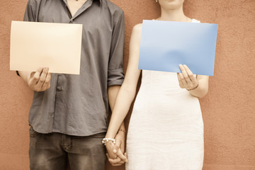 Closeup couple holding hands and holding frames at wall background