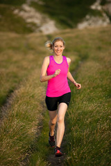 beautiful young woman runns cross country on a mountian path at