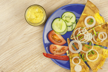 Scrambled egg omelet with vegetables on a wooden table. Preparation of fast food home.
