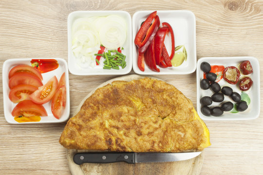 Scrambled egg omelet with vegetables on a wooden table. Preparation of fast food home.
