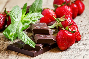Delicious milk chocolate with strawberries and mint, selective f