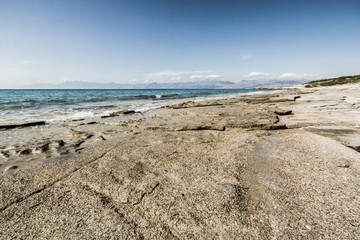 Shore of Ionian sea with flat rocks on the beach