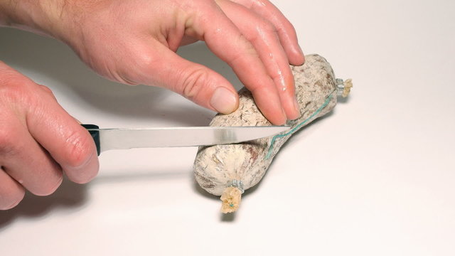 Slicing slice of salami with knife