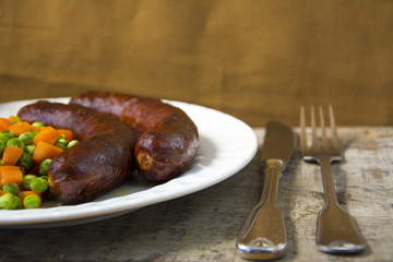 Sausages with vegetables on a white plate 