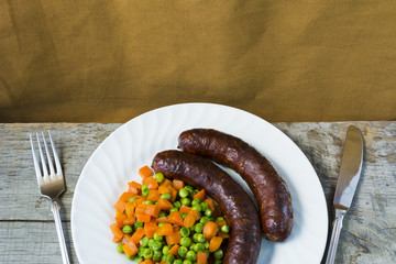 Sausages with vegetables on a white plate 