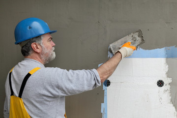 Wall insulation, spreading mortar over mesh and styrofoam