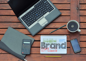 work place with notebook with note about: Brand with laptop and coffee on table