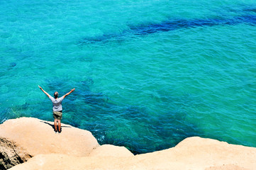 man with his arms in the air in front of the ocean