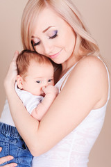 Smiling young woman holding little child. Happy mother with her newborn baby. Motherhood