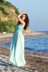 Fototapeta na wymiar Portrait of woman at the beach wearing long coral dress