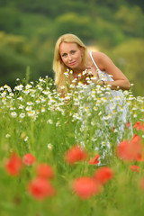 Naklejka na ściany i meble Pregnant happy woman in a flowering poppy field outdoors