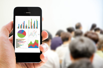 Close-up hand holding mobile phone with analyzing graph