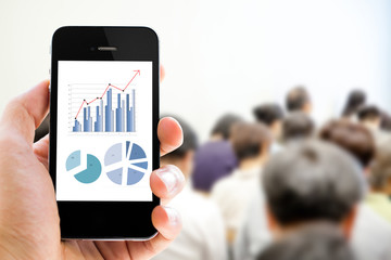 Close-up hand holding mobile phone with analyzing graph