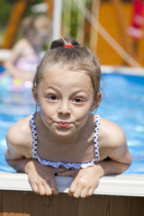 Child girl in blue bikini near swimming pool. Hot Summer