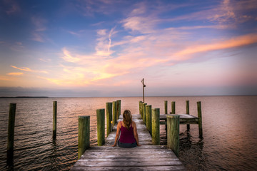 Woman watching a sunset from a pier on the Chesapeake bay in Maryland