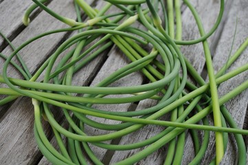 Bunches of freshly picked garlic scape on a wooden table