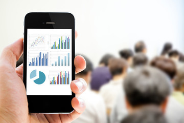 Close-up hand holding mobile phone with analyzing graph