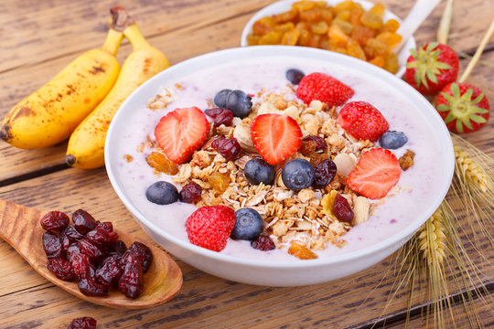 Healthy breakfast with fresh fruits, yogurt and granola on rustic wooden table